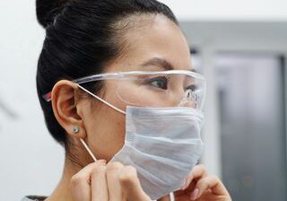 An image of a female doctor putting on a surgical mask during the covid pandemic